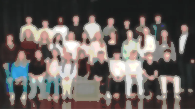 Eine Gruppe von Menschen posierte auf einer Bühne vor einem dunklen Hintergrund für ein Foto; einige saßen, andere standen.
